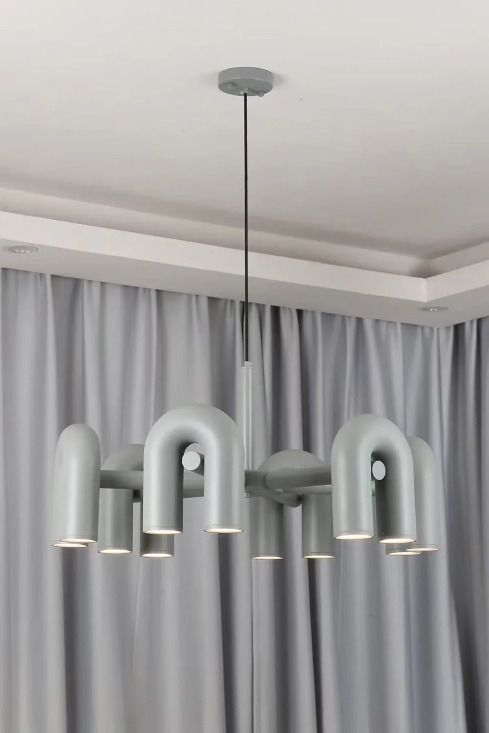 Lampa wisząca z cylindrycznymi punktami świetlnymi na łukowatych ramionach