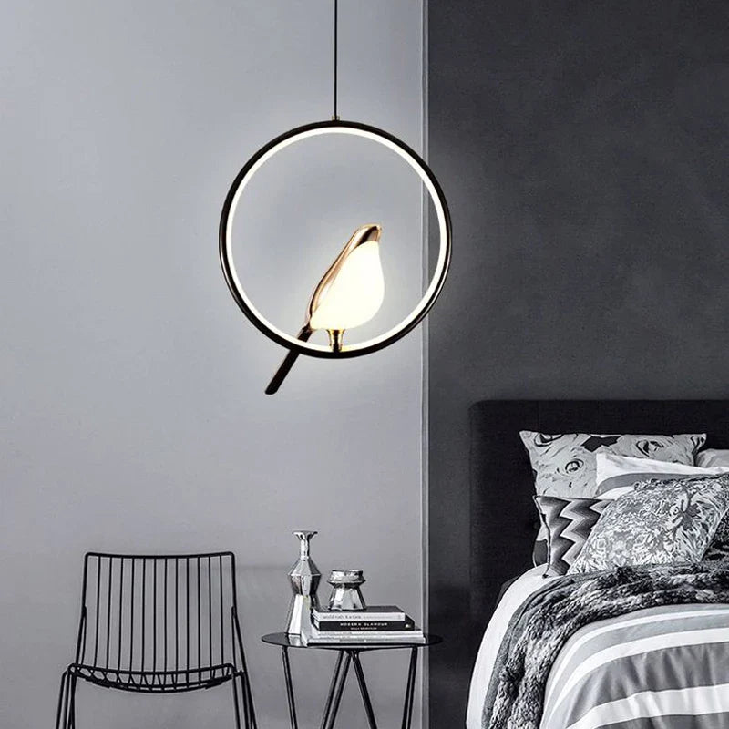 Wisząca lampa LED z okrągłym, świecącym pierścieniem i złotą figurką ptaka na grzędzie
