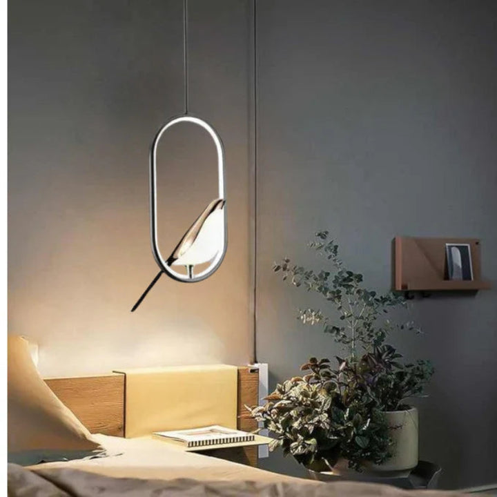 Wisząca lampa LED z okrągłym, świecącym pierścieniem i złotą figurką ptaka na grzędzie